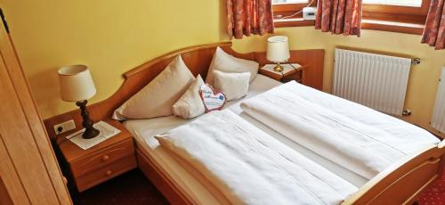 sypialnia z łóżkiem z białymi prześcieradłami i poduszkami w obiekcie Ferienwohnung w mieście Bad Kleinkirchheim