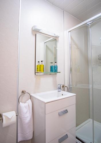 a white bathroom with a sink and a shower at Arvon House in Llandudno
