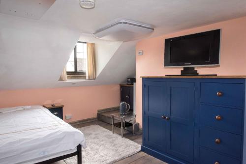 a bedroom with a blue dresser with a tv on top at Robinas Cotswold Coach House in Witney