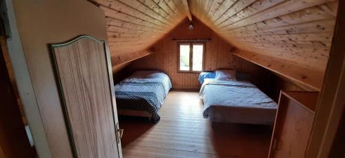 LingrevilleにあるCHALET BORD DE MERのベッド2台と窓が備わる屋根裏部屋です。