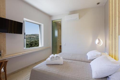 a white bedroom with two beds with towels on them at SpilGaia in Spílion