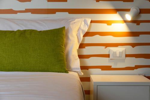 a bed with a green pillow and a side table at All'Orologio - Boutique Hotel in Caorle