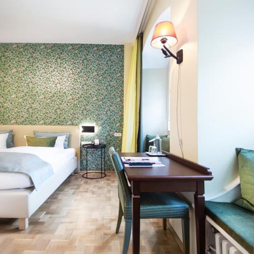 a bedroom with a bed and a desk and a bed and a bed at Romantik Hotel Barbarossa in Konstanz