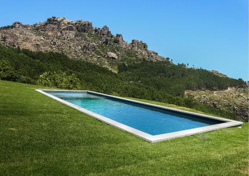 a swimming pool in the middle of a grass field at Hostel Retiro do Gerês in Geres