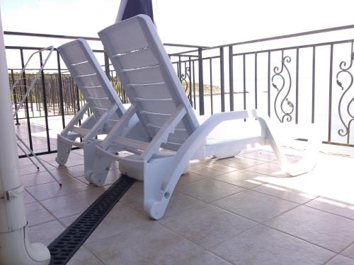 two white rocking chairs sitting on a balcony at Villa Lazuren Bryag 2 in Chernomorets