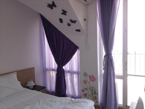 a bedroom with purple curtains and a bed and a window at Villa Lazuren Bryag 2 in Chernomorets