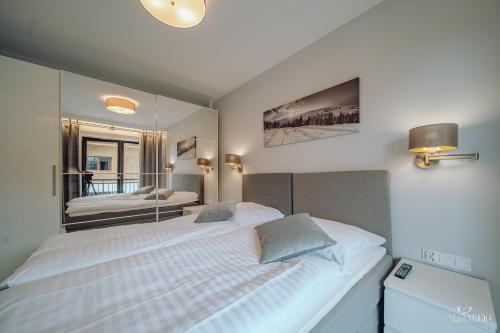 a bedroom with a large white bed and a mirror at Apartament Silence Karpatia Resort z Kominkiem in Karpacz