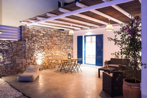 a room with a stone wall and a table and chairs at Punda Villas Paros in Kampos Paros