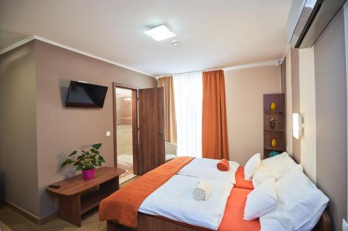 a bedroom with a bed with an orange and white blanket at Park-Lak Vendégház in Makó