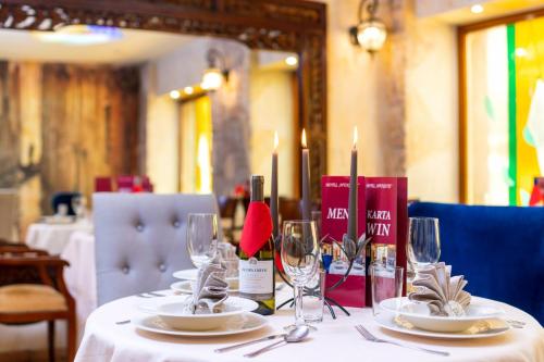 a table with a white table cloth with candles and wine glasses at Hotel Wenecki in Częstochowa