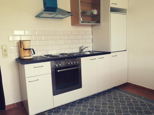 a kitchen with white cabinets and a stove top oven at Haus Im Grünen in Villach