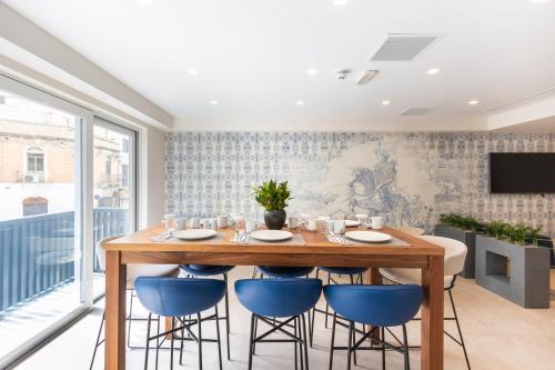 a dining room with a wooden table and blue chairs at The G Hotel by JL in St Julian's