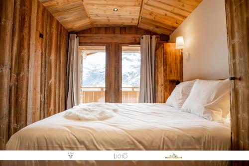 a bed in a room with a large window at Marmotte 205 - Splendide duplex aux pieds des pistes in Bonneval-sur-Arc