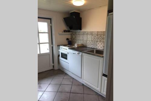 a kitchen with a sink and a stove top oven at Gammelt Mandø hus Hyggebo in Ribe