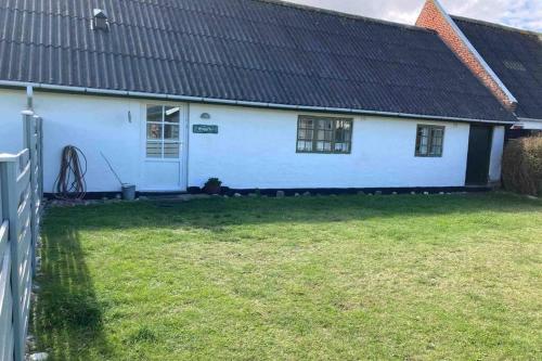 a white house with a black roof and a yard at Gammelt Mandø hus Hyggebo in Ribe