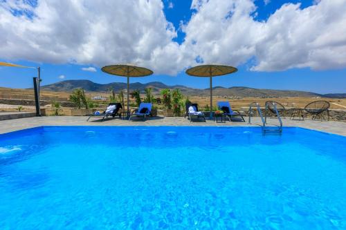 a large swimming pool with chairs and umbrellas at Punda Villas Paros in Kampos Paros