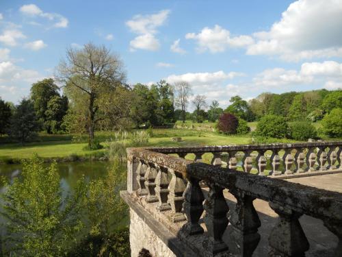 a stone bridge over a river in a park at Le Logis d'Equilly in Équilly