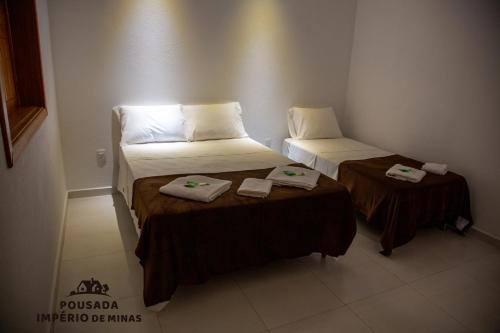 two beds in a room with towels on them at Pousada Império de Minas in Capitólio