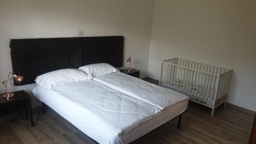 a bed with white sheets and a crib in a bedroom at Appartamento Le Rose in Ossuccio