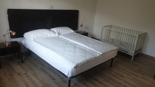 a bedroom with a bed with white sheets and a crib at Appartamento Le Rose in Ossuccio