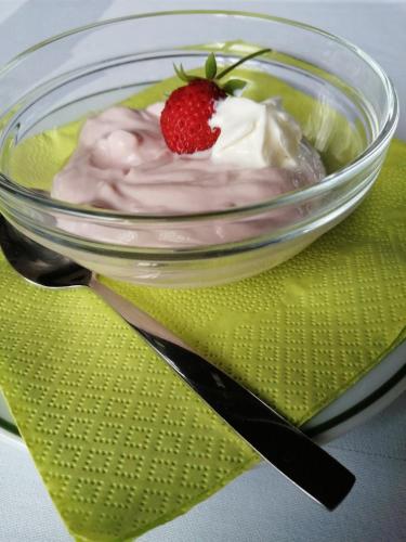 a bowl of yogurt and a strawberry on a green napkin at Hotel Lugerhof in Weiding