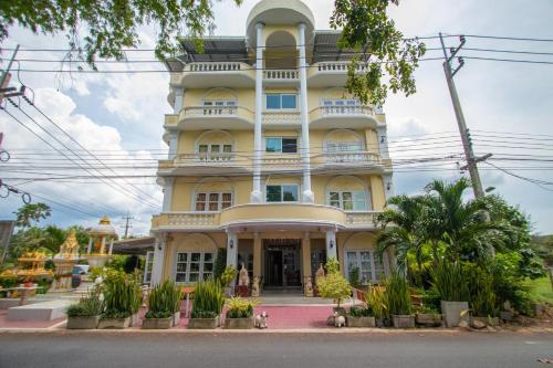 a large yellow building with many windows at Anchalee Resort in Bang Saphan