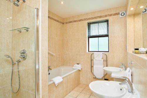 La salle de bains est pourvue d'une baignoire, d'un lavabo et d'une douche. dans l'établissement Bunratty Manor Hotel, à Bunratty