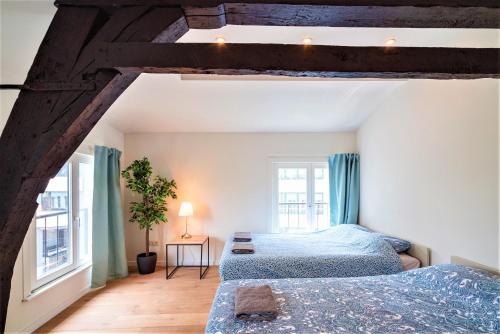 two beds in a room with two windows at The Main Square Residence in Antwerp