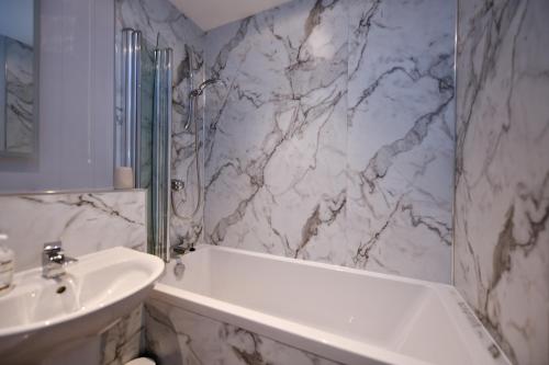 a bathroom with a white tub and a sink at Troon Executive Apartment in Troon