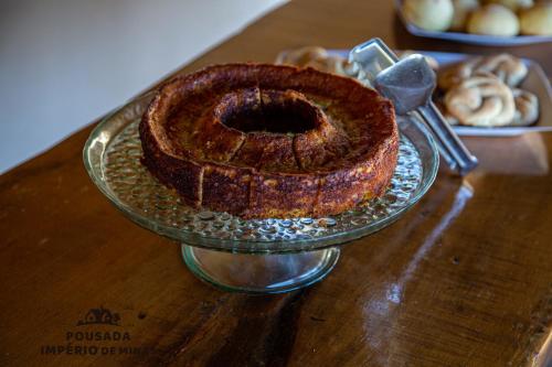 a cake on a glass plate on a table at Pousada Império de Minas in Capitólio