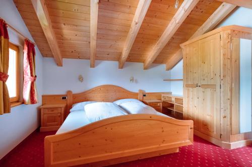 a bedroom with a wooden bed in a room at Residence Alpenrose in Rasùn di Sotto
