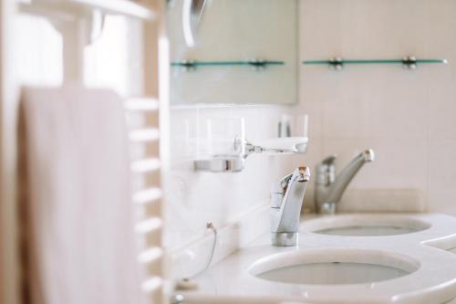 a white bathroom with two sinks and a mirror at Residence Alpenrose in Rasùn di Sotto