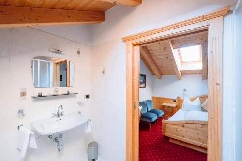 a bathroom with a sink and a bed in a room at Residence Alpenrose in Rasùn di Sotto