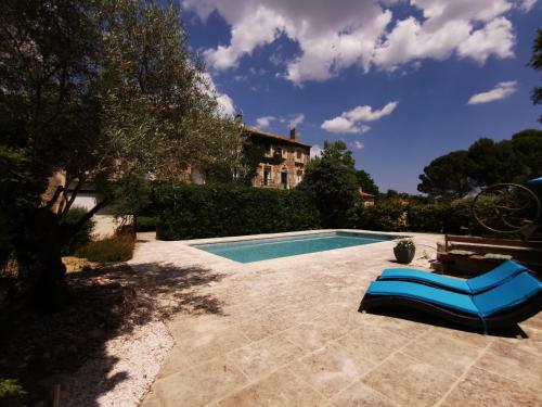 a swimming pool with a blue lounge chair next to a house at Les Chambres du Lavoir Vert in Tourbes