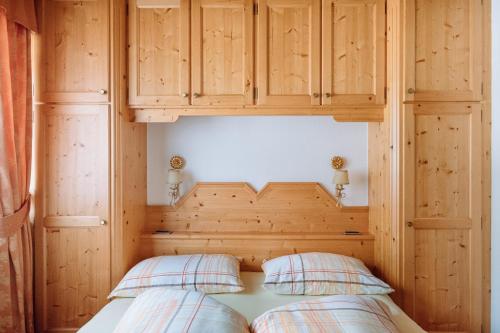 a bedroom with a wooden headboard and two pillows at Residence Alpenrose in Rasùn di Sotto