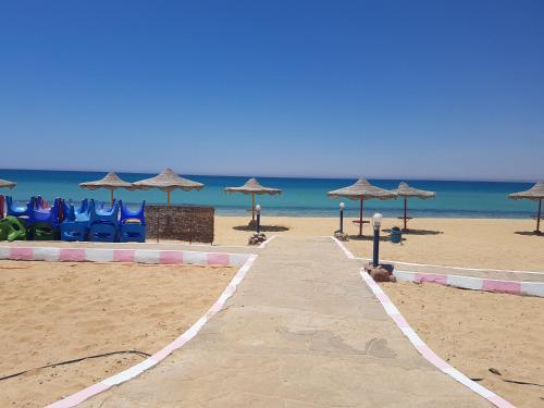 a sandy beach with umbrellas and chairs and the ocean at Golden Beach 1 for family in Ras Sedr