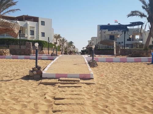 a sandy beach with some buildings and palm trees at Golden Beach 1 for family in Ras Sedr