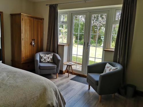 a bedroom with two chairs and a bed and windows at White Cottage B and B in Spilsby