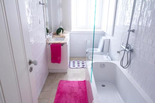a bathroom with a tub and a toilet and a pink rug at Guest House Amoreiras in Lisbon