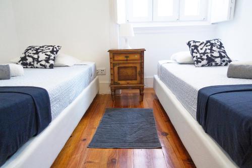 two beds in a room with a wooden floor at Guest House Amoreiras in Lisbon