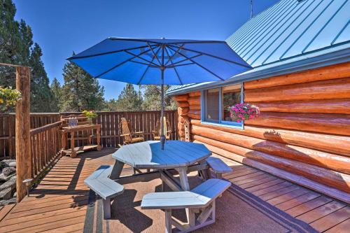 a wooden deck with a table and an umbrella at Bend Log Cabin with Cascade Mountain Views! in Bend