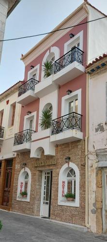 a pink and white building with windows and balconies at Hotel Diana in Koroni