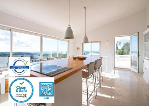 a kitchen with a large island with chairs and windows at Sea View Cascais Design Villa in Alcabideche