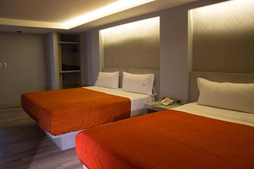 a room with two beds with orange and white sheets at Hotel El Senador in Mexico City