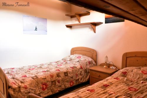 a bedroom with two beds and a night stand at Mansarda Caviola in Falcade