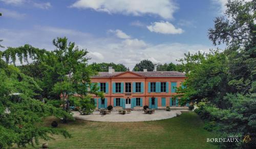 レオニャンにあるChateau Pont Saint-Martinの青い窓と庭のある大きなオレンジ色の家