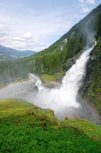 a waterfall in the middle of a valley with trees at Ursprung Panorama Hotel Königsleiten in Königsleiten