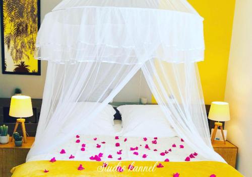 een bed met een hemelbed met roze bloemen erop bij Charmant studio Kannèl au MANGANAO vue sur mer et panier d'accueil offert in Saint-François