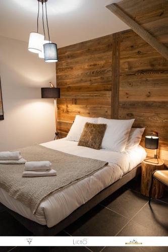 une chambre avec un grand lit avec un mur en bois dans l'établissement MARMOTTE 204 - Charmant appartement mansardé, aux pieds des pistes, à Bonneval-sur-Arc