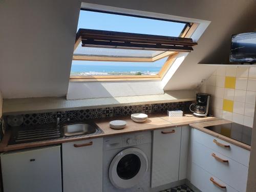 une cuisine avec une fenêtre et un lave-linge dans l'établissement appartement vue mer GOELAND, à Le Portel
